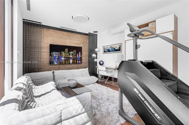 exercise room featuring hardwood / wood-style flooring and a wall unit AC