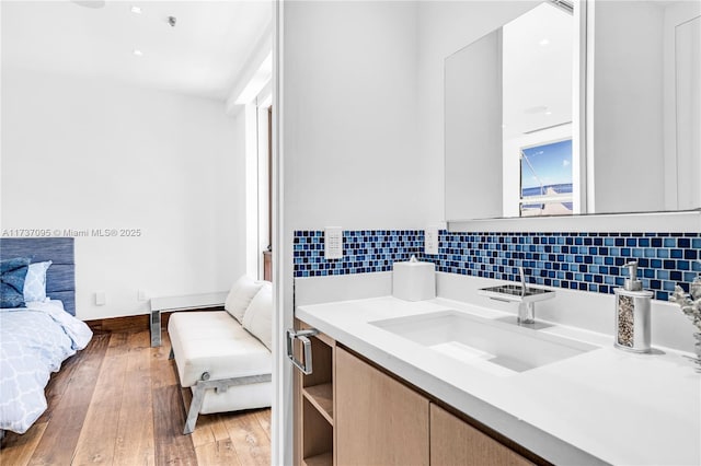 bathroom with hardwood / wood-style flooring, vanity, and tasteful backsplash