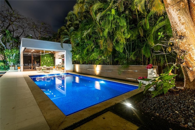 pool at night featuring an outbuilding and a patio