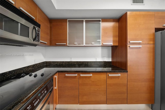 kitchen with stainless steel appliances and dark stone counters