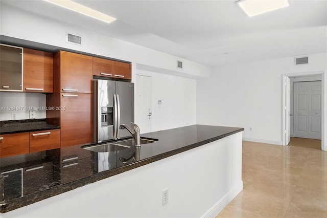 kitchen featuring dark stone countertops, sink, and stainless steel refrigerator with ice dispenser