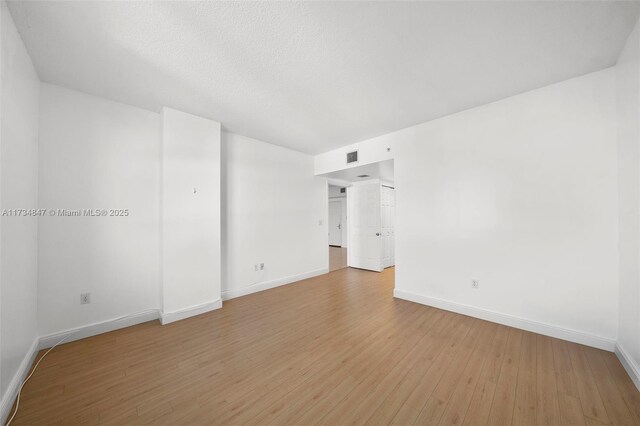 unfurnished room with light hardwood / wood-style flooring and a textured ceiling