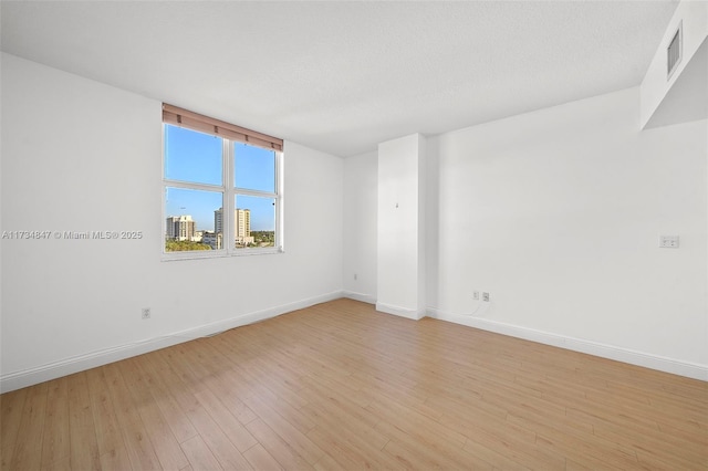 spare room with light hardwood / wood-style floors and a textured ceiling