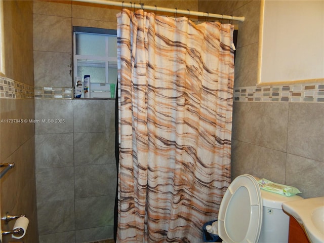 bathroom featuring walk in shower, vanity, toilet, and tile walls