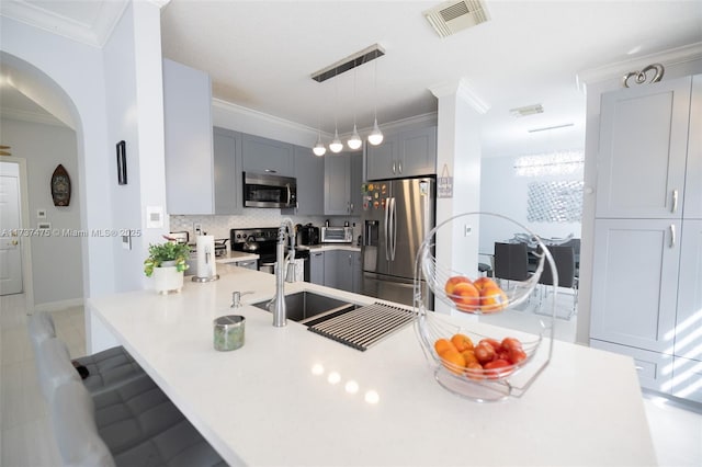 kitchen with a breakfast bar, gray cabinetry, crown molding, pendant lighting, and stainless steel appliances