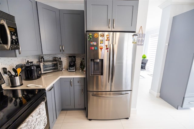 kitchen with tasteful backsplash, appliances with stainless steel finishes, gray cabinets, and light tile patterned floors