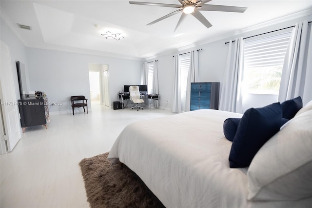 bedroom featuring hardwood / wood-style flooring, ceiling fan, ornamental molding, and a raised ceiling