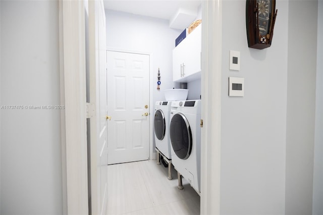 laundry room with cabinets, washer and dryer, and light tile patterned floors