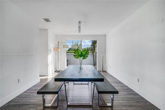 dining room with visible vents, a textured wall, baseboards, and wood finished floors