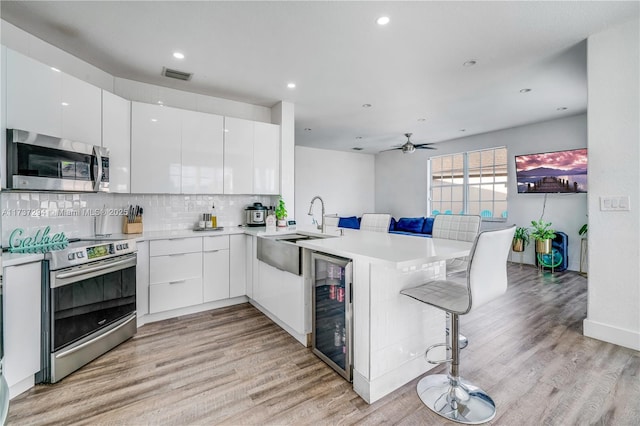 kitchen featuring white cabinetry, a kitchen bar, kitchen peninsula, and appliances with stainless steel finishes