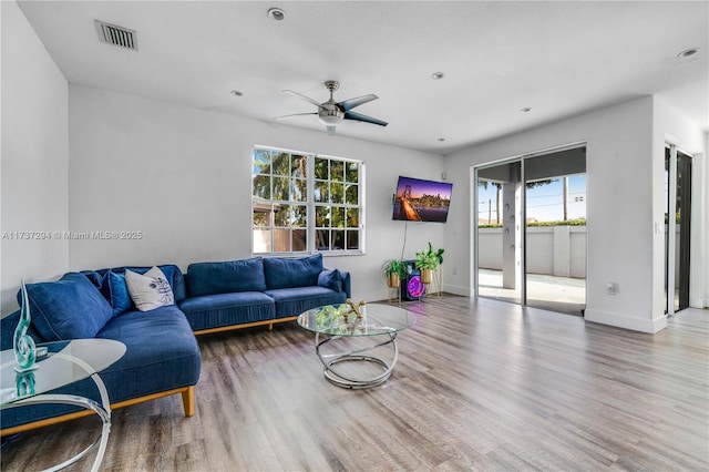 living area with visible vents, ceiling fan, baseboards, and wood finished floors