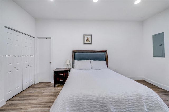 bedroom with hardwood / wood-style flooring, electric panel, and a closet