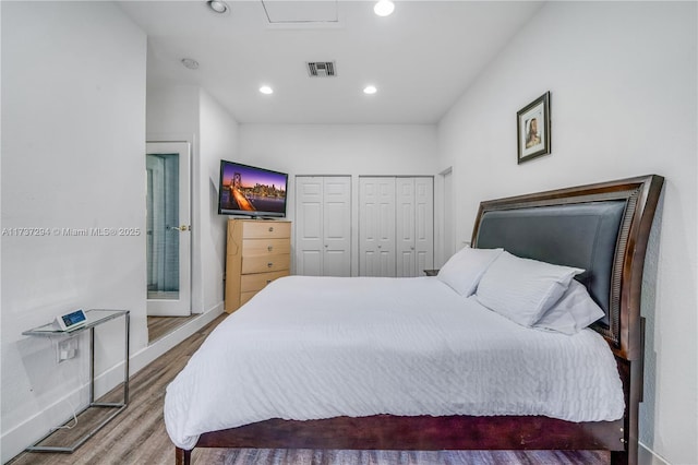 bedroom featuring multiple closets and hardwood / wood-style floors