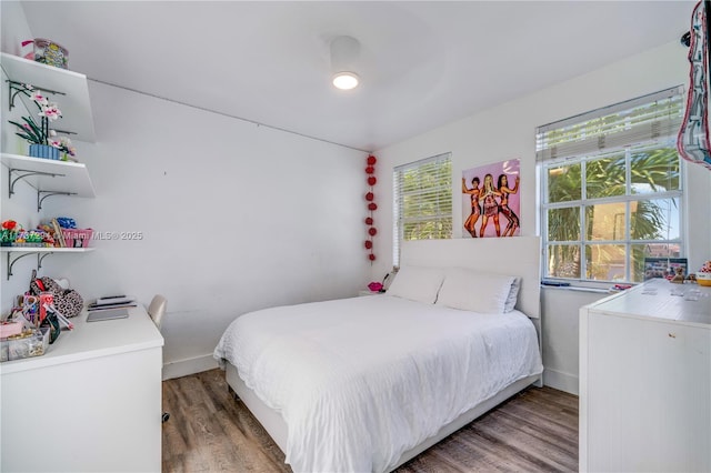 bedroom featuring multiple windows, wood finished floors, and baseboards