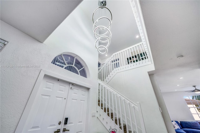 stairs with ceiling fan and a towering ceiling