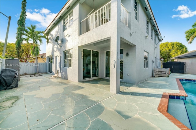 rear view of house with a patio area, fence, a fenced in pool, and stucco siding