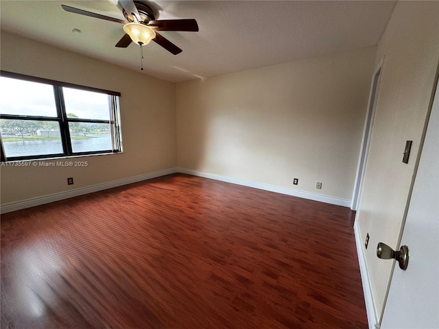 unfurnished room featuring a water view, ceiling fan, and dark hardwood / wood-style flooring