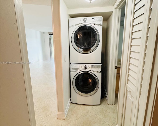 washroom with stacked washer / drying machine and light tile patterned flooring