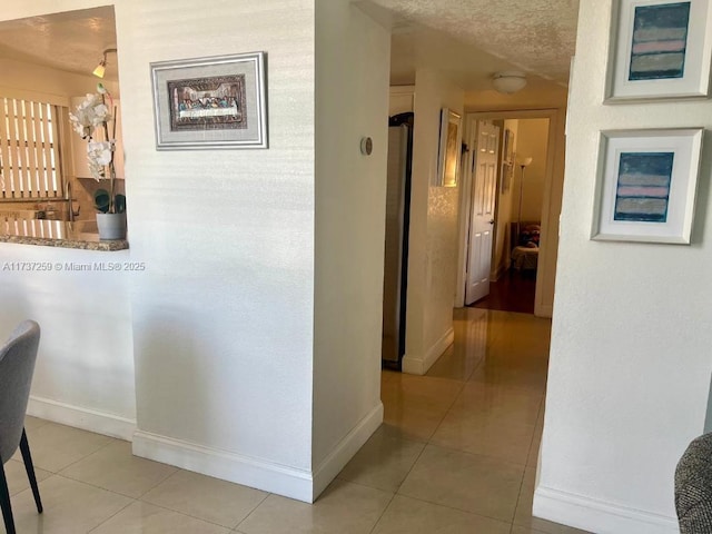 hallway featuring light tile patterned floors and a textured ceiling