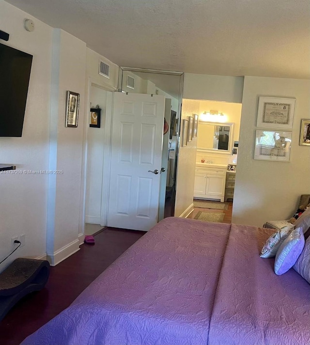 bedroom featuring connected bathroom and hardwood / wood-style flooring