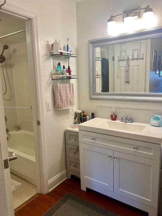 bathroom with wood-type flooring, tiled shower / bath combo, and vanity