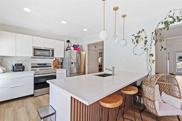 kitchen with white cabinetry, sink, pendant lighting, and stainless steel appliances