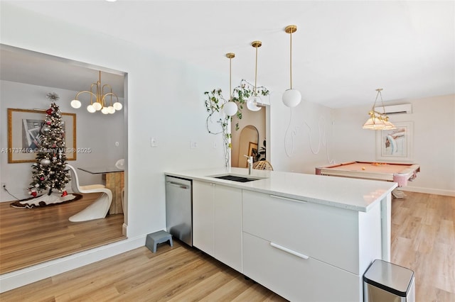 kitchen with sink, dishwasher, white cabinetry, decorative light fixtures, and kitchen peninsula