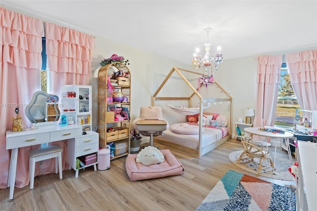 bedroom with multiple windows, a notable chandelier, and light wood-type flooring