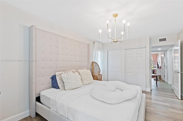 bedroom featuring light hardwood / wood-style flooring, a chandelier, and a closet