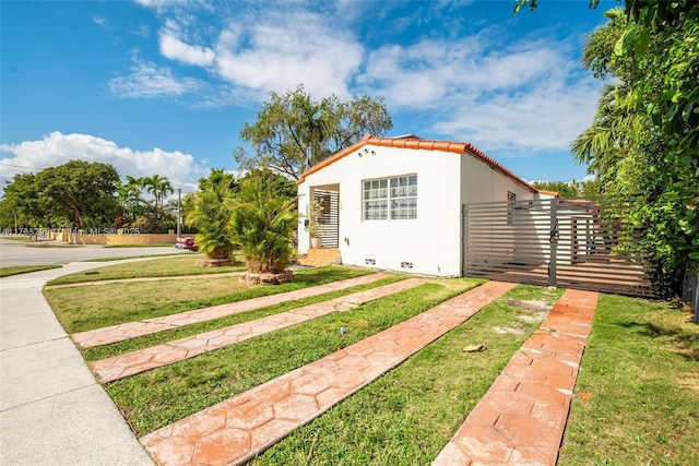 exterior space featuring entry steps, a tile roof, fence, a front lawn, and stucco siding