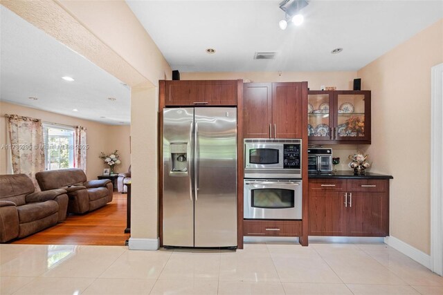 2039 SW 17th St, Miami, FL 33145 - kitchen featuring stainless steel appliances, glass insert cabinets, light tile patterned floors, dark countertops, and recessed lighting