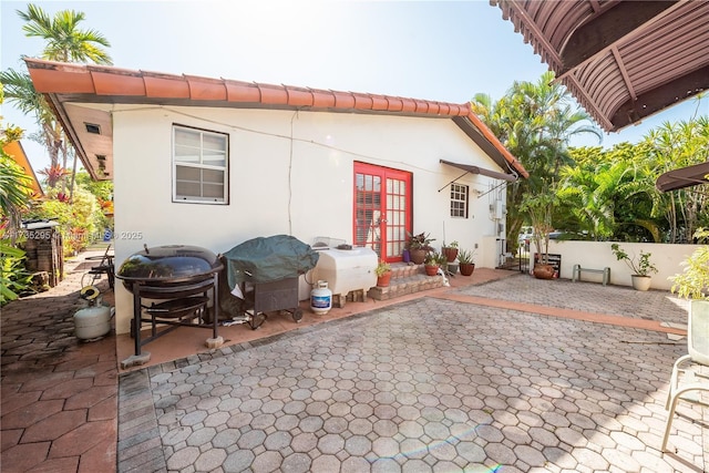 rear view of property with stucco siding, fence, a patio, and french doors