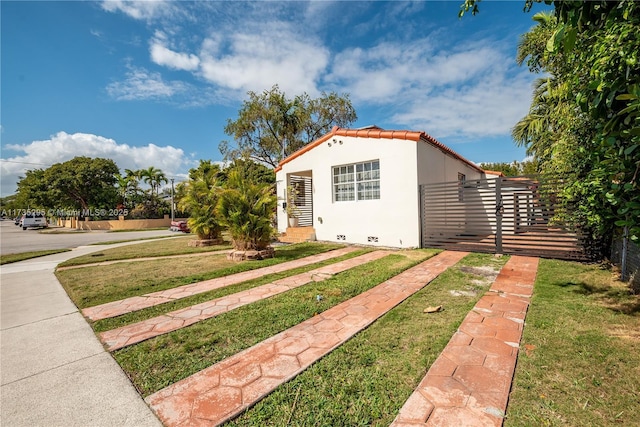 view of front of home with a tile roof, crawl space, fence, a front lawn, and stucco siding