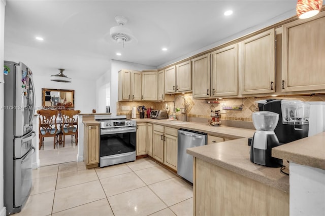 kitchen with sink, tasteful backsplash, light tile patterned floors, light brown cabinets, and appliances with stainless steel finishes