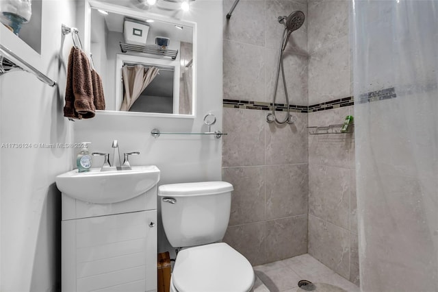 bathroom with vanity, toilet, and tiled shower