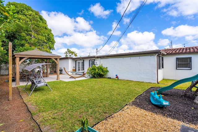 rear view of property featuring a gazebo, a yard, a playground, and a patio