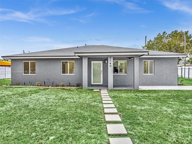 view of front of property featuring fence, a patio area, a front lawn, and stucco siding