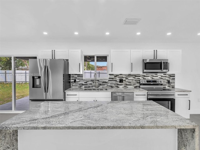 kitchen with white cabinets, tasteful backsplash, appliances with stainless steel finishes, and a sink