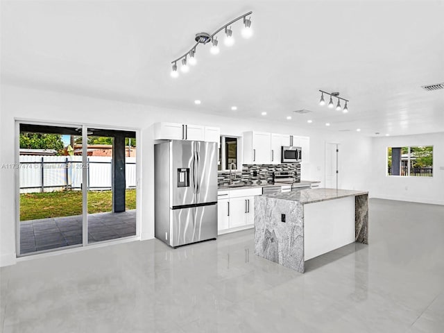 kitchen featuring light stone countertops, a healthy amount of sunlight, stainless steel appliances, and visible vents