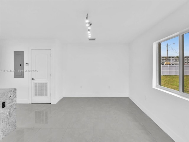 tiled empty room with electric panel, baseboards, and visible vents