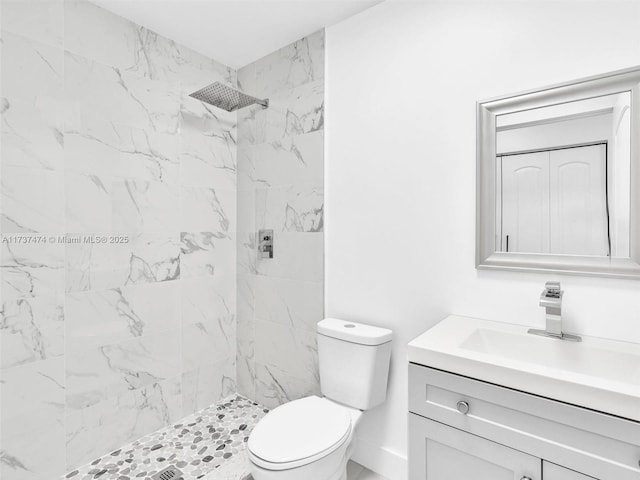 bathroom with toilet, vanity, and a tile shower