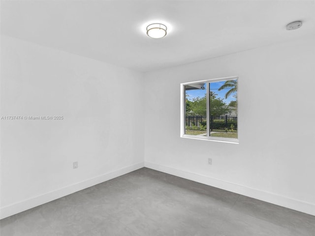 spare room with baseboards and concrete floors
