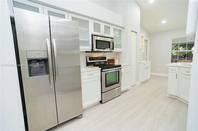 kitchen with white cabinetry, lofted ceiling, appliances with stainless steel finishes, and light wood-type flooring