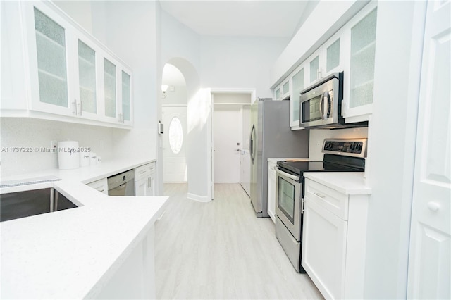 kitchen with appliances with stainless steel finishes, sink, white cabinets, and light hardwood / wood-style flooring