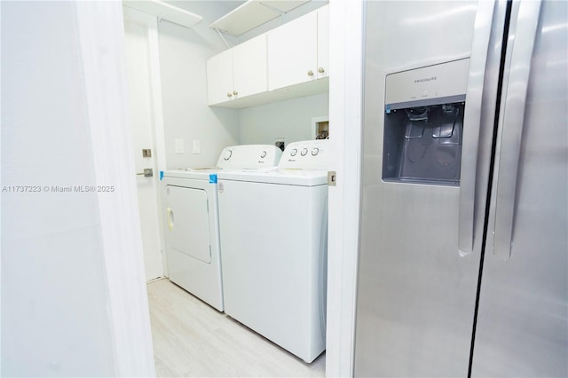 laundry room featuring cabinets, light hardwood / wood-style floors, and washer and dryer