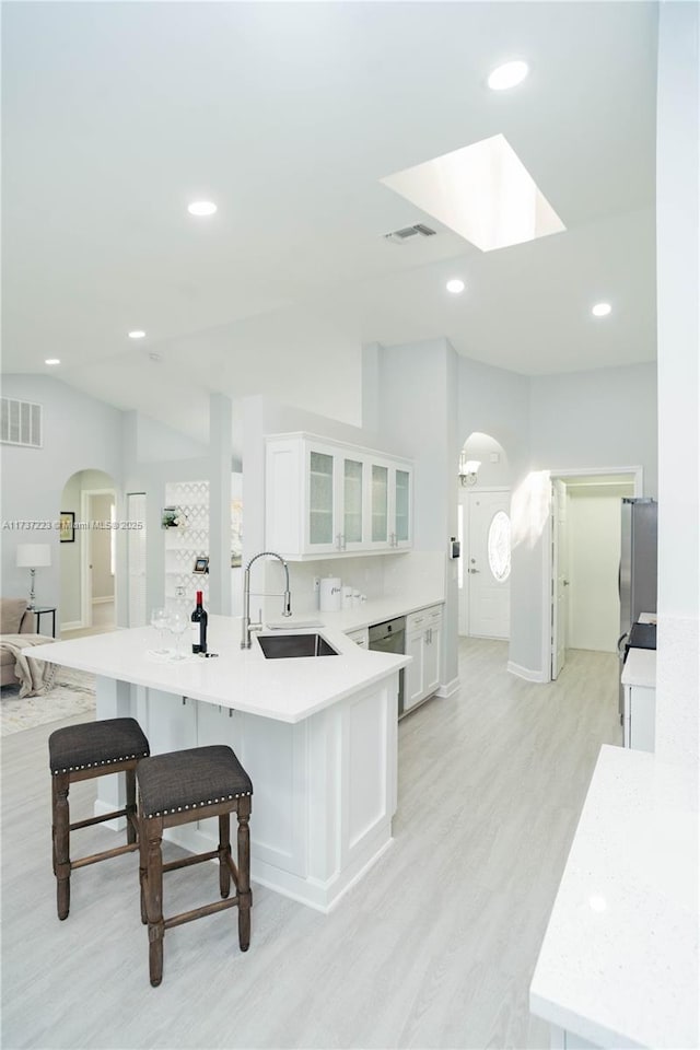 kitchen with sink, white cabinetry, a kitchen breakfast bar, kitchen peninsula, and light hardwood / wood-style floors