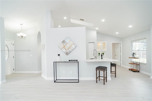 kitchen with lofted ceiling, a breakfast bar, sink, light wood-type flooring, and pendant lighting