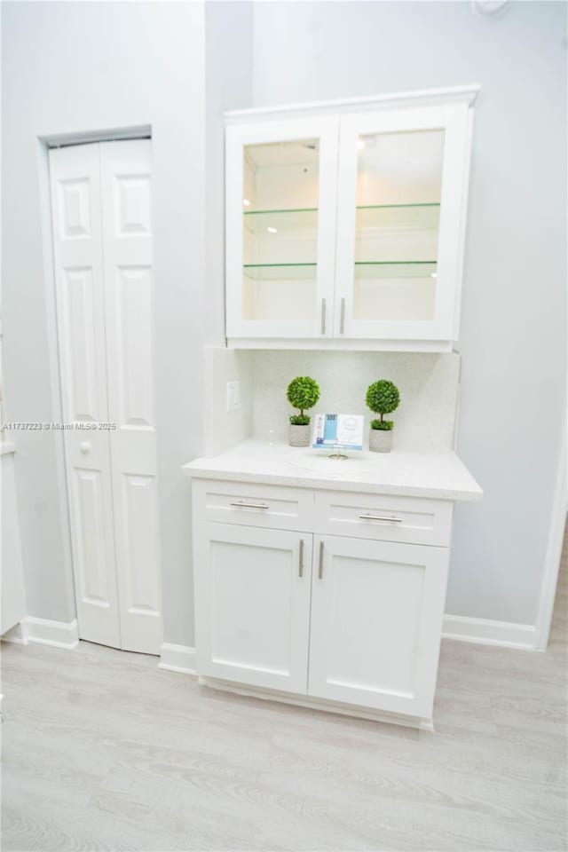 bar featuring backsplash, white cabinets, and light hardwood / wood-style floors