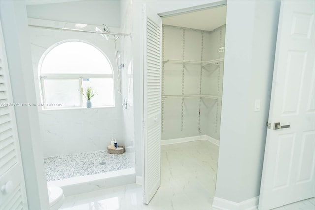 bathroom featuring a tile shower and toilet