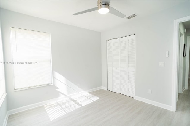 unfurnished bedroom featuring ceiling fan, light wood-type flooring, and a closet